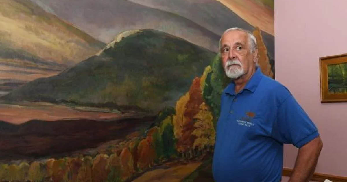 Jan Lokuta poses in front of an artwork of the Susquehanna River